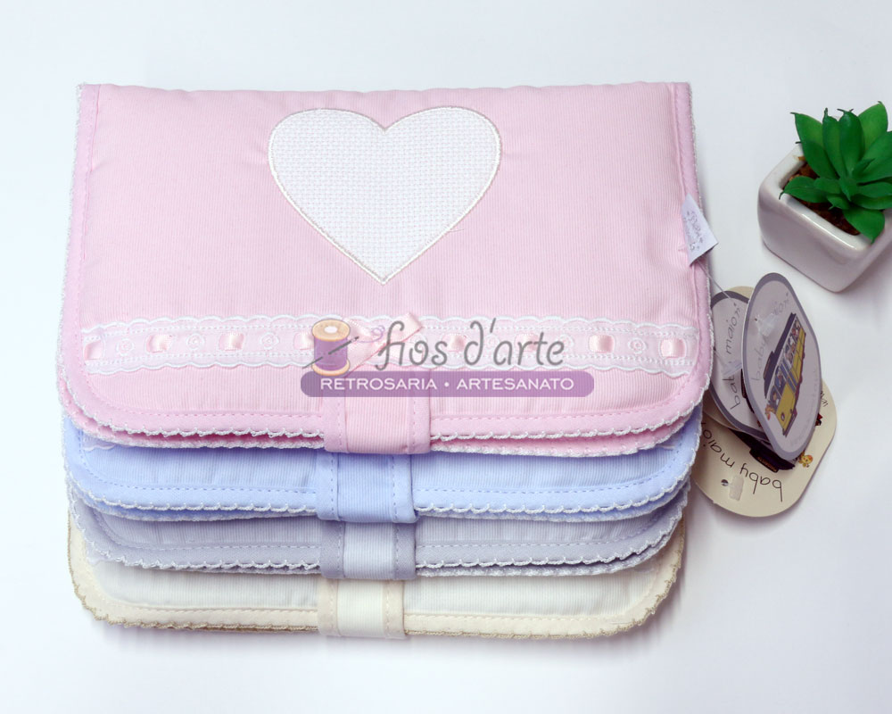 Capas de almofadas em várias cores pastel com bordados em forma de coração e detalhes rendados.