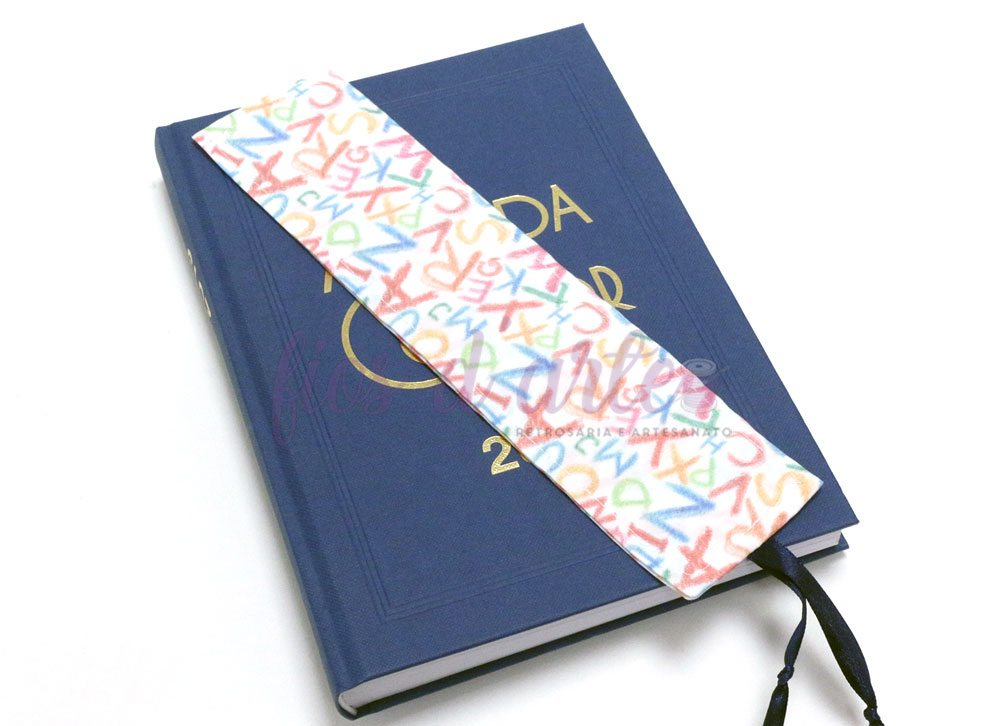 Marcador de livro de tecido branco com letras coloridas sobre agenda azul 2022