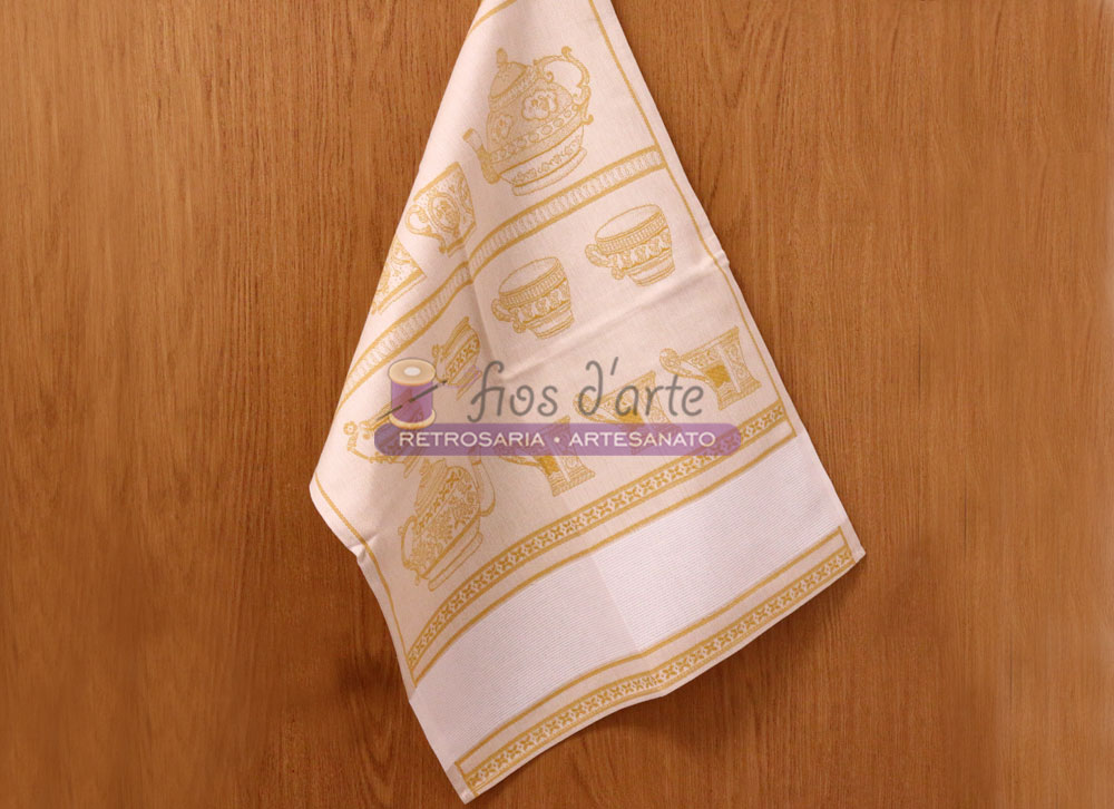 Pano de cozinha branco com estampas douradas de sushi pendurado numa porta de madeira