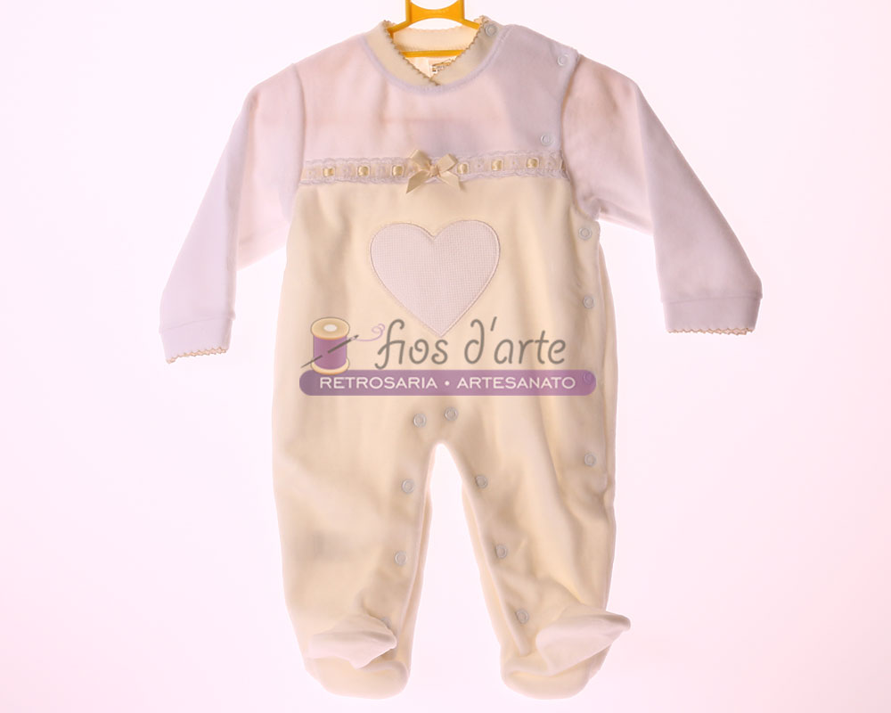 Macacão de bebé creme e branco com coração bordado e botões, pendurado num cabide amarelo