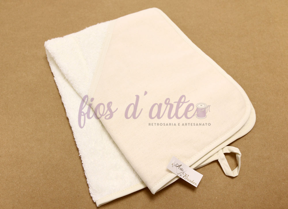 Toalha felpuda branca e creme com etiqueta fios d'arte sobre fundo castanho