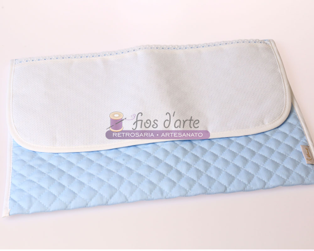 Tecido acolchoado azul claro com tecido branco liso e etiqueta com texto sobre superfície branca