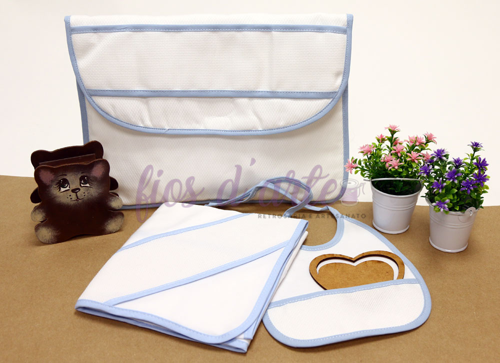Conjunto branco com detalhes azuis para bebé, com babete, toalha e saco organizador, com vasos de flores decorativos ao lado