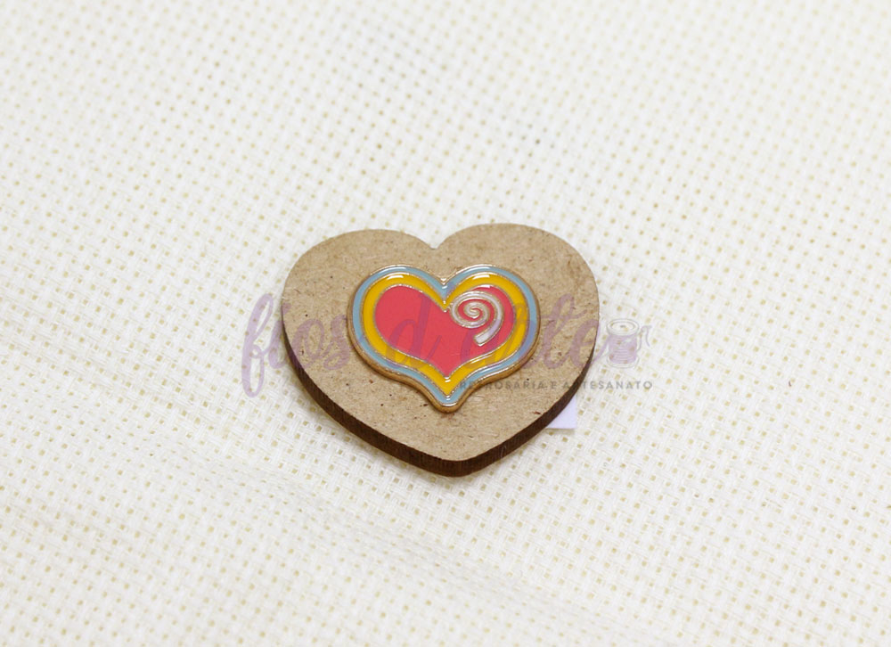 Íman coração de madeira com pintura colorida sobre tecido branco de quadrados pequenos