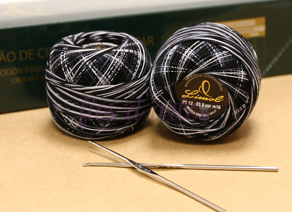 Dois novelos de fio para crochet preto e branco com agulhas metálicas sobre superfície bege
