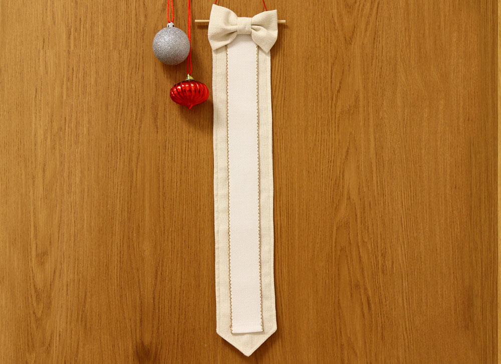 Marcador de páginas branco com laço pendurado em parede de madeira com bolas decorativas