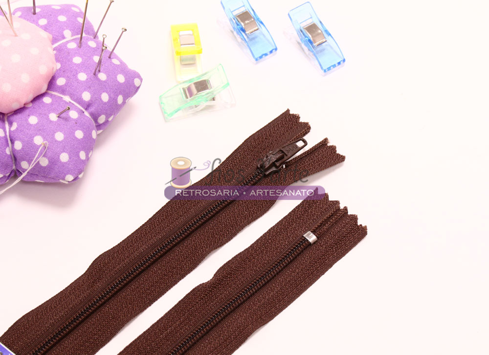 Acessórios de costura castanhos, clips coloridos e alfineteiro roxo com bolinhas