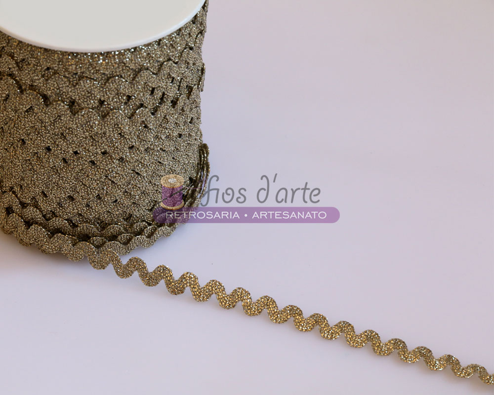 Fita decorativa ondulada dourada com brilho sobre superfície clara