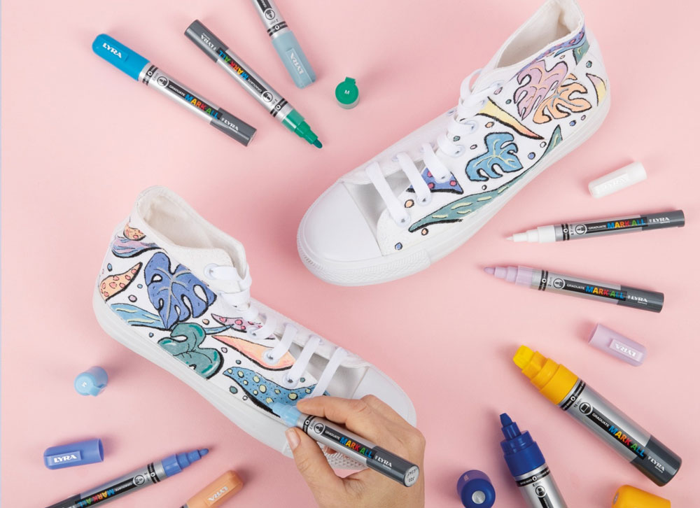 Sapatilhas brancas customizadas com desenhos coloridos e canetas ao redor