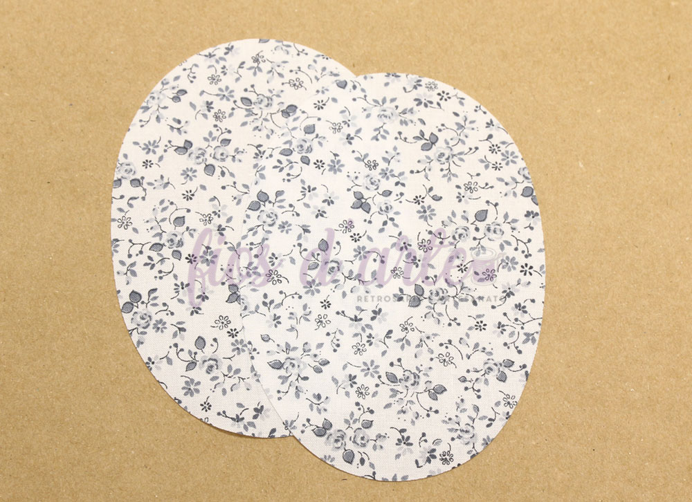 Dois brincos ovais em papel com padrão floral cinzento em fundo branco