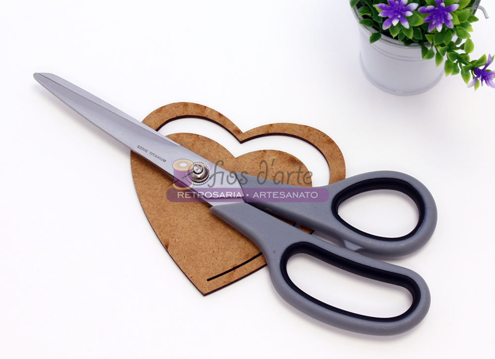 Tesoura para costura (Mediac) - Tam 18 Tesoura preta e cinza sobre molde de coração em madeira com planta em vaso ao lado