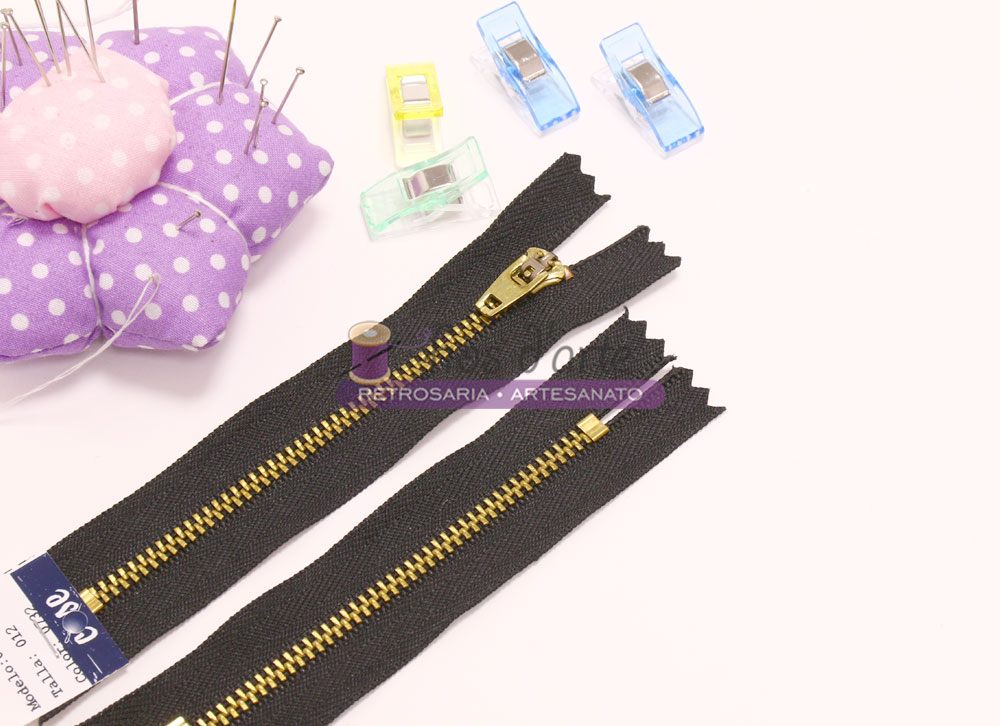 Fecho éclair preto, clips coloridos e alfineteiro floral lila sobre fundo branco