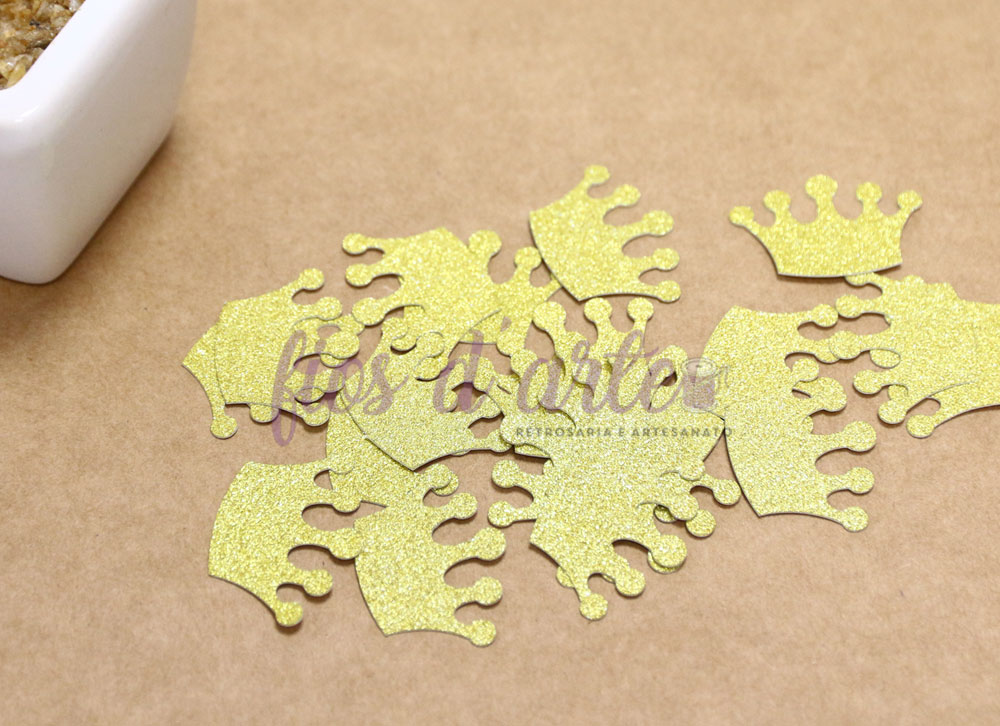 Coroas douradas em glitter em superfície castanha com recipiente branco