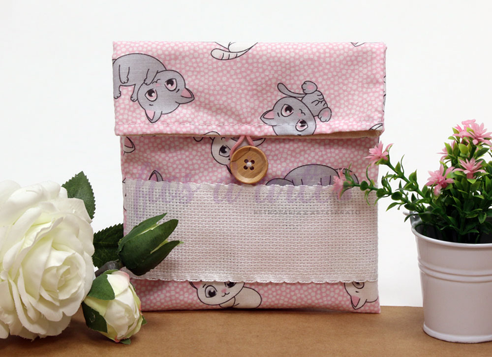 Bolsa rosa com padrão de gatos e botão de madeira entre flores artificiais