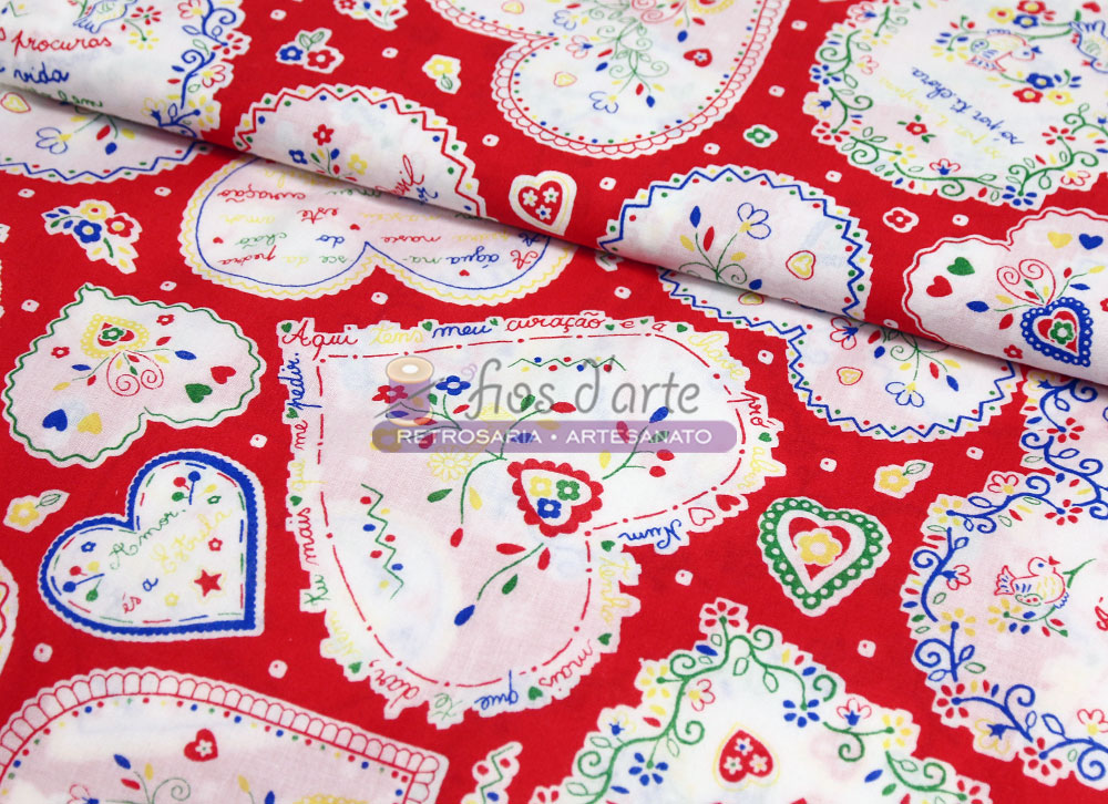 Tecido vermelho com padrão de corações brancos coloridos e texto em português.