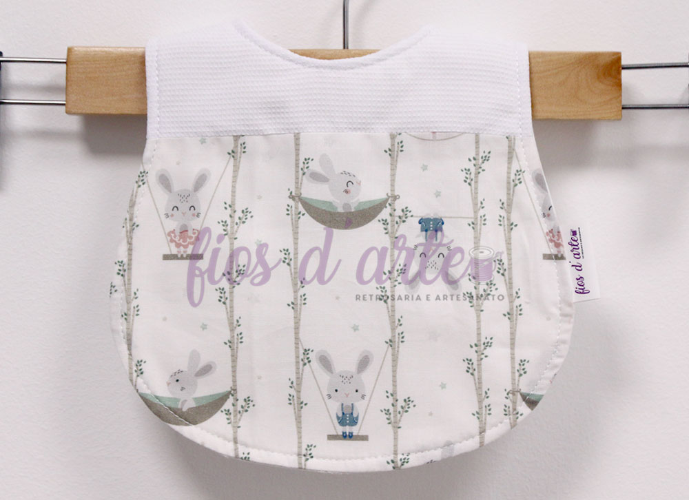 Babete com turco plastificado - Coelhinhos (Fios d'arte) Babete com padrão de coelhos e folhas verdes em fundo branco