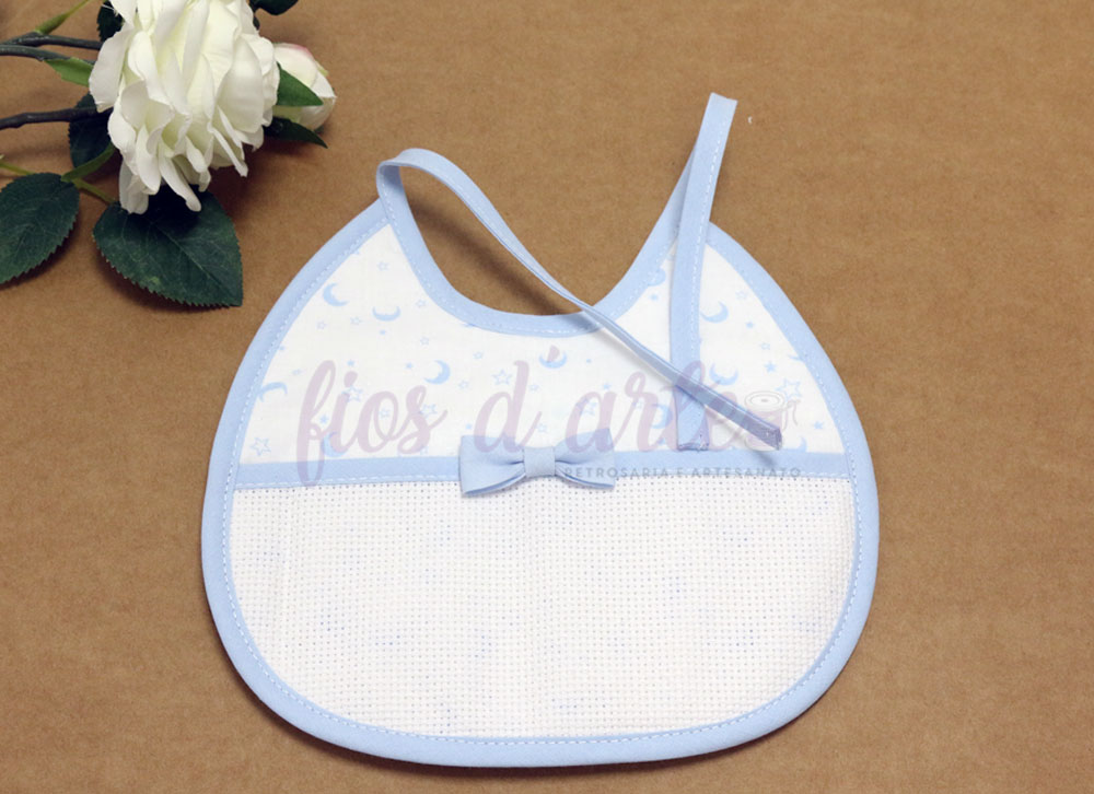 Babete com lacinho com turco para bordar ponto cruz - Estrelas e Luas (Fios d'arte) Babete de bebé branco com padrão azul e laço azul