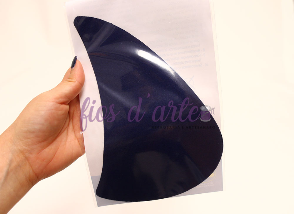 Entrepernas termocolantes II - azul marinho Placa flexível preta brilhante segurada por uma mão com papel branco ao fundo