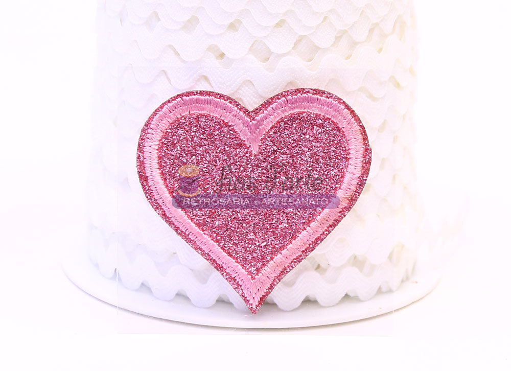 Adesivo cor-de-rosa brilhante em forma de coração sobre fundo branco texturizado.