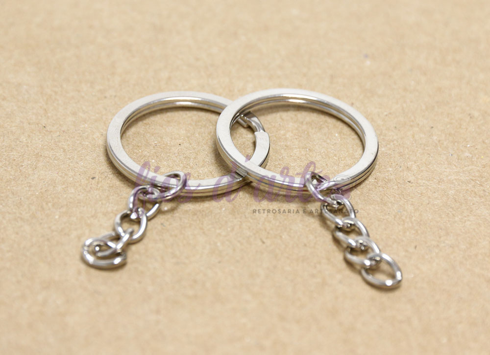 Dois anéis prateados com corrente numa superfície castanha lisa