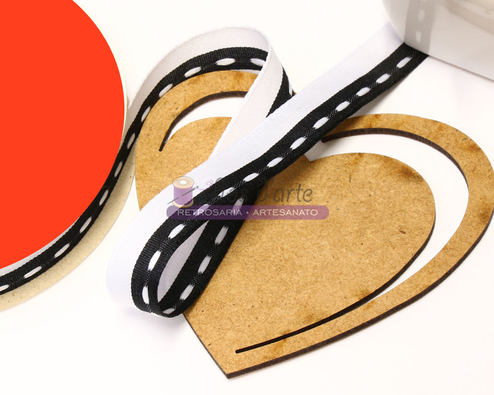 Fita preta com pontos brancos sobre base em forma de coração de madeira clara