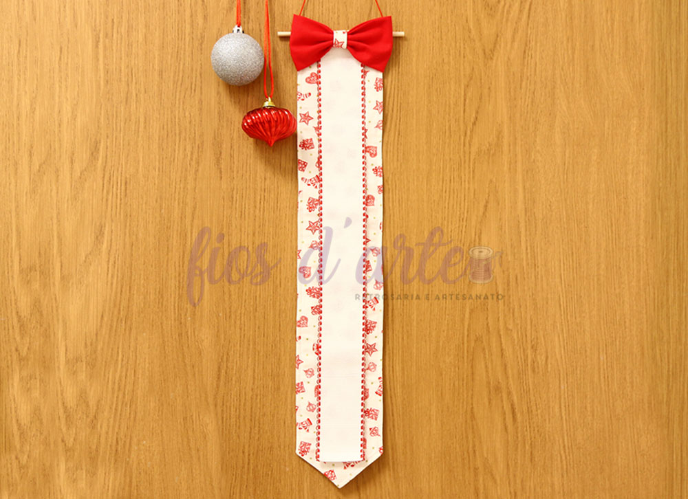 Fita decorativa branca com padrão vermelho e laço vermelho pendurada em madeira