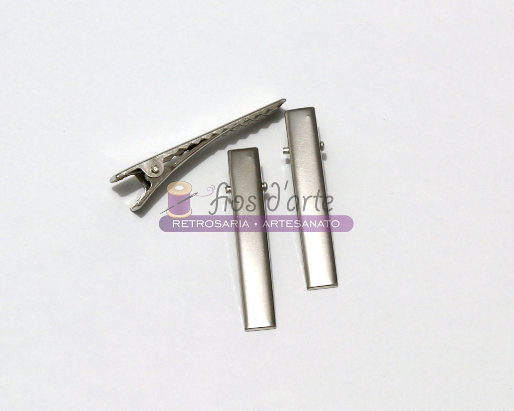 Gancho bico de pato para cabelo (5,5cms) Três presilhas metálicas prateadas sobre fundo branco com logótipo e texto.