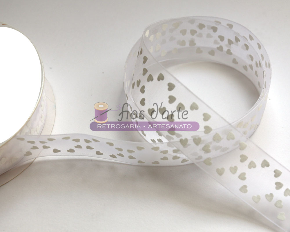 Fita transparente com padrão de corações brancos enrolada junto a uma bobina