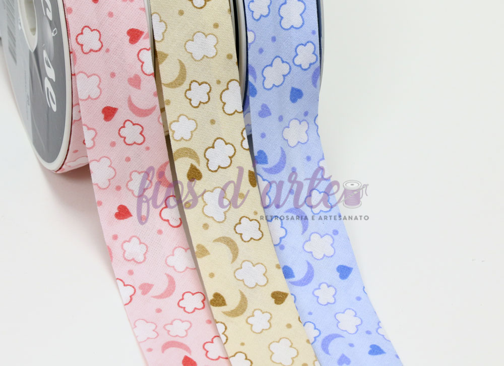 Três fitas decorativas em rolos com estampas de nuvens e luas, nas cores rosa, bege e azul.