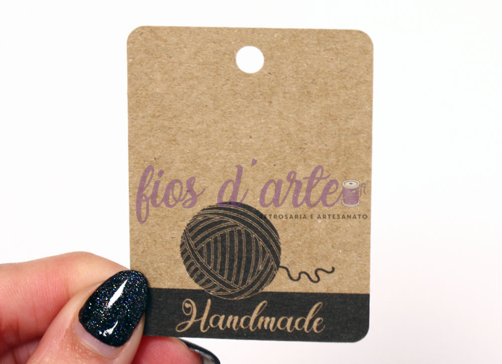 Etiqueta de cartão marrom com ilustração de novelo e texto 'fios d'arte Handmade'