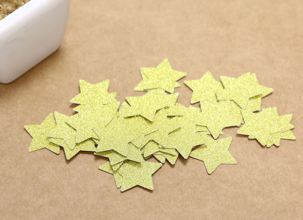 Estrelas douradas de papel glitter sobre superfície castanha