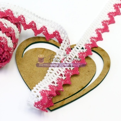 Fita de renda em crochet rosa e branca sobre suporte em coração de madeira