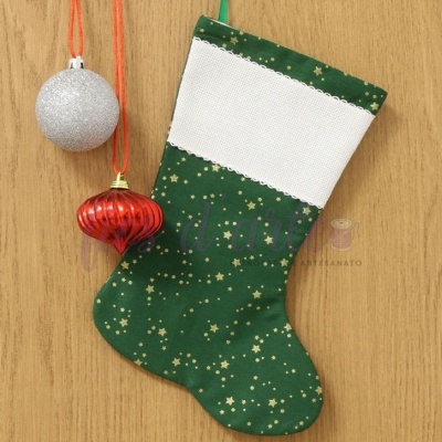 Meia de Natal verde com estrelas douradas e punho branco pendurada numa parede de madeira com bolas de Natal prateada e vermelha