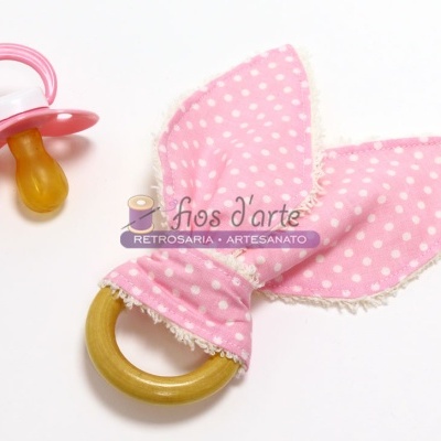 Chupeta cor-de-rosa e mordedor de madeira com tecido cor-de-rosa de bolinhas brancas