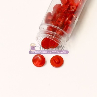 Frasco plástico com botões vermelhos redondos sobre superfície branca