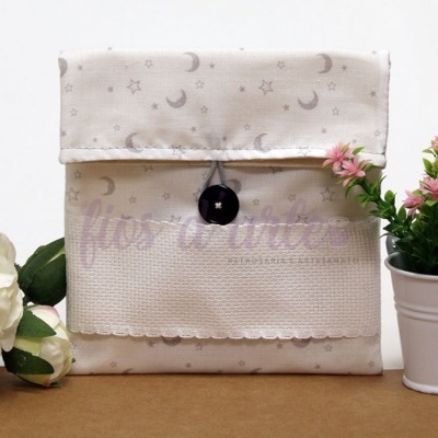 Bolsa de tecido bege com padrão de luas e estrelas e botão preto