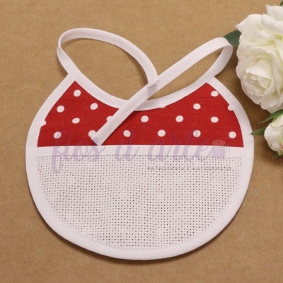 Babeiro redondo vermelho e branco com padrão de bolas, próximo de flores brancas.