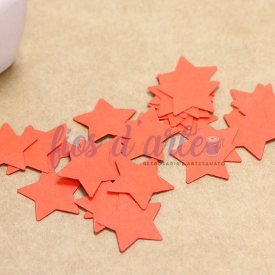 Estrelas de papel vermelho recortadas sobre superfície castanha