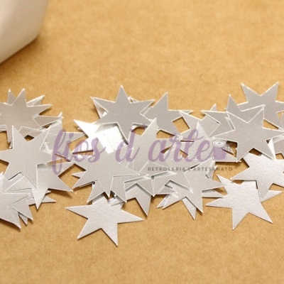 Estrelas prateadas recortadas em papel sobre superfície castanha