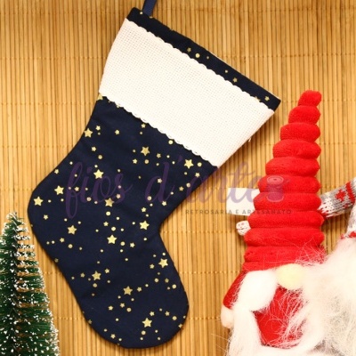 Meia de Natal azul com estrelas douradas e punho branco junto a gnomos e árvore de Natal