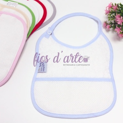 Biberões com tetina sobre toalha azul e planta com flores rosas