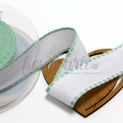 Fita branca com borda verde em carretel transparente sobre base em forma de coração de cartão