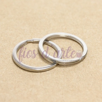 Dois aneis metálicos prateados e lisos sobre superfície de cartão castanho