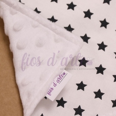 Manta para bebé branca com estrelas pretas e textura de bolinhas.