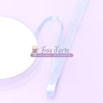 Fita de cetim azul clara enrolada numa bobina branca sobre fundo lilás