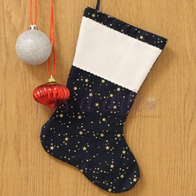 Meia de Natal azul com estrelas douradas e punho branco junto a duas bolas de Natal, pendurada numa superfície de madeira clara.