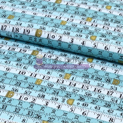 Tecido azul claro com padrão de réguas de medir em branco e preto com detalhes dourados