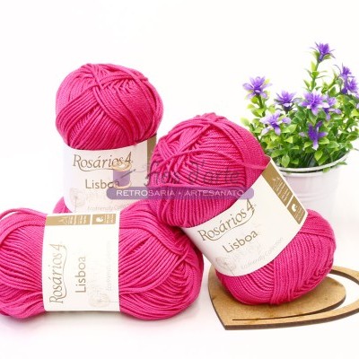 Quatro novelos de lã cor-de-rosa e vaso de flores roxas