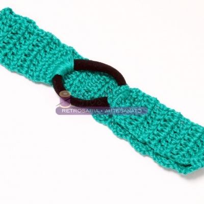 Faixa de cabelo verde água em croché com elástico preto e etiqueta da marca