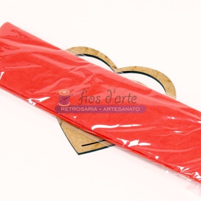 Pacote de tecido vermelho em plástico transparente sobre fundo com desenho de coração de madeira clara